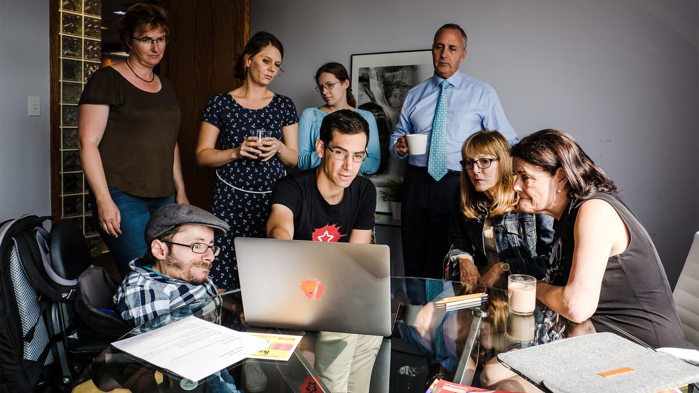 Menschen sitzen um einen Laptop